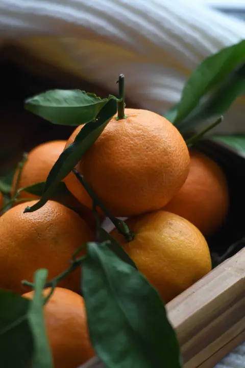 Orangen mit Blättern in einer Holzkiste